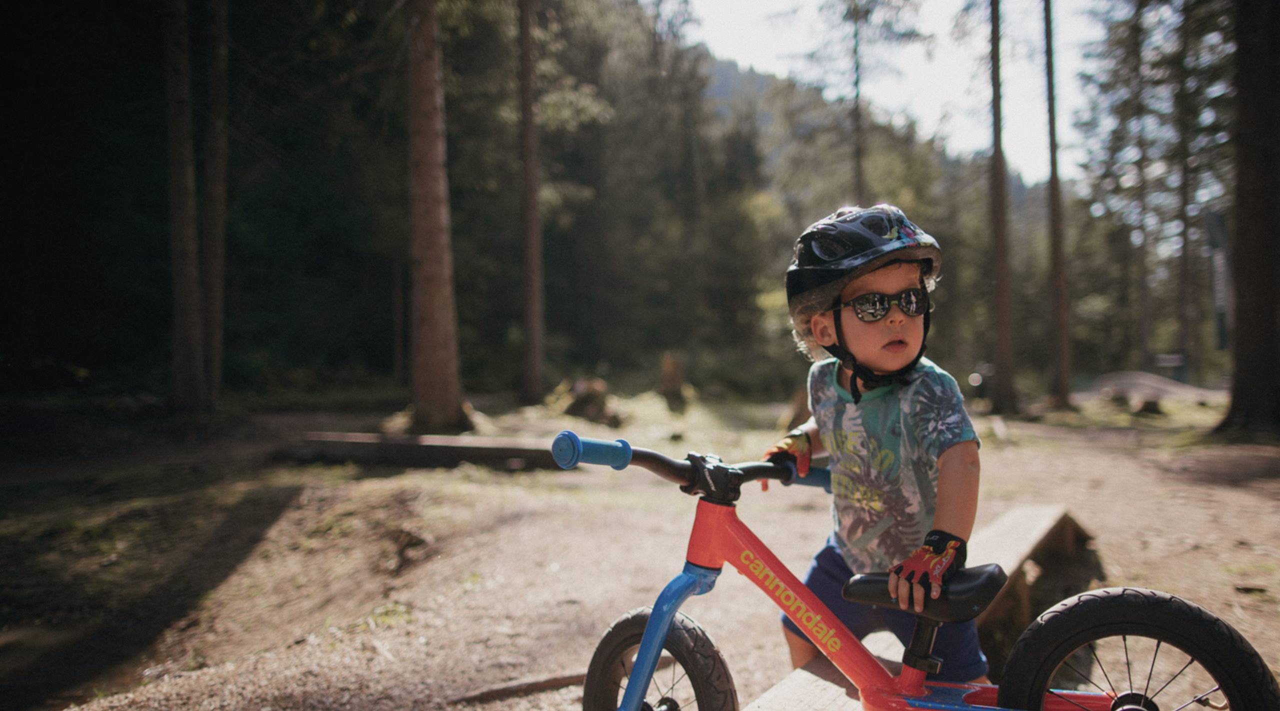 Enfant casqué sur Cannondale rouge en forêt — LuxBikes Doncols